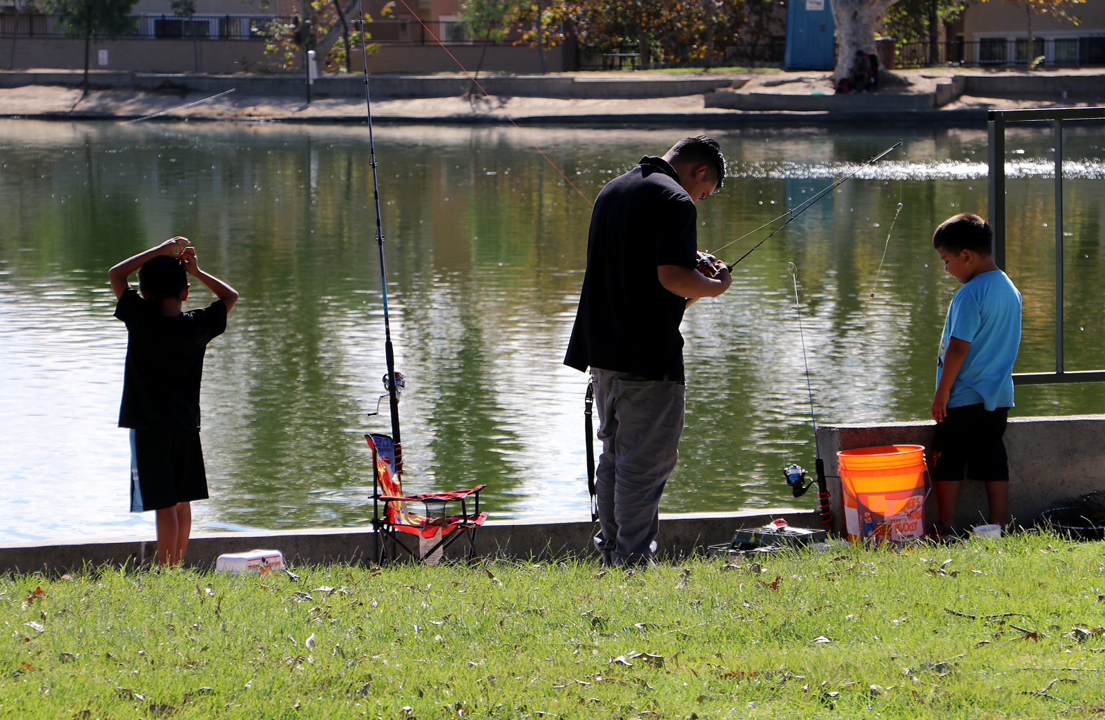 Father fishing with two boys at Guasti park.