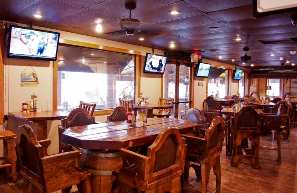 Inside the Pirates Cove restaurant. Wooden tables and chairs with TV screens on the wall.
