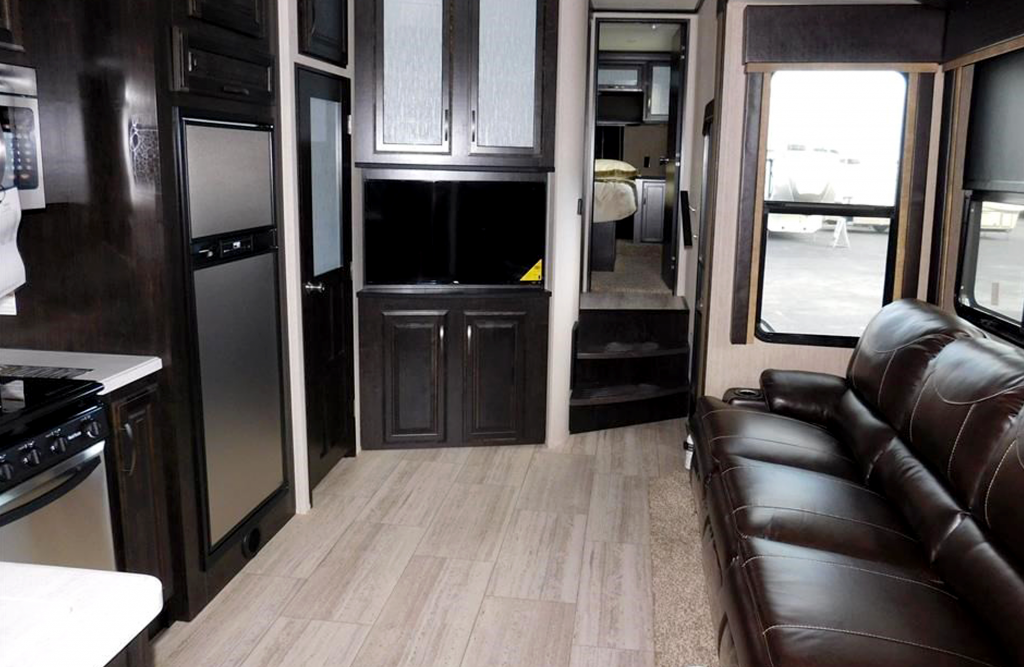 Upscale RV shows leather couch and stainless steel appliances.