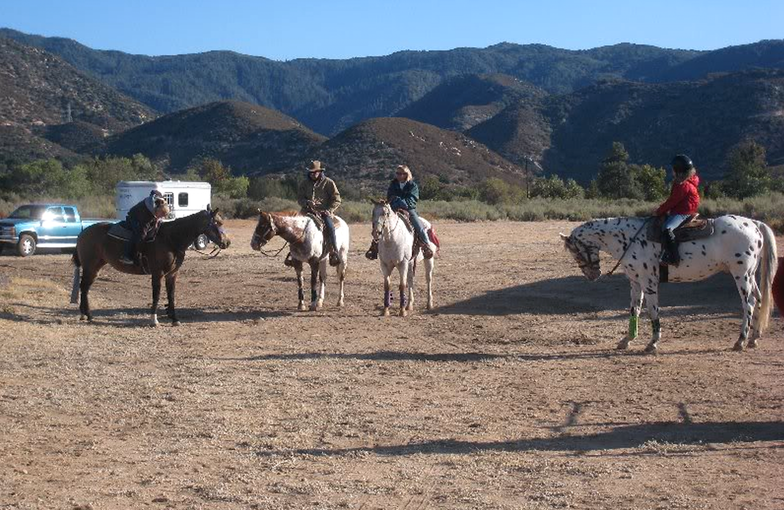 A group of people on horseback in a dirt open area of the park.
