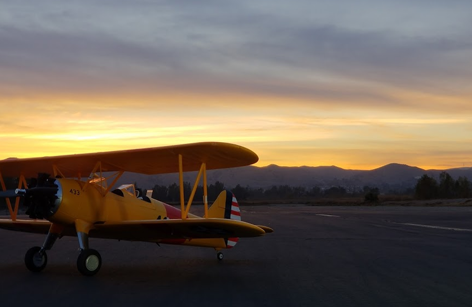 A closeup of a model airplane on the Prado park airfield at dusk.
