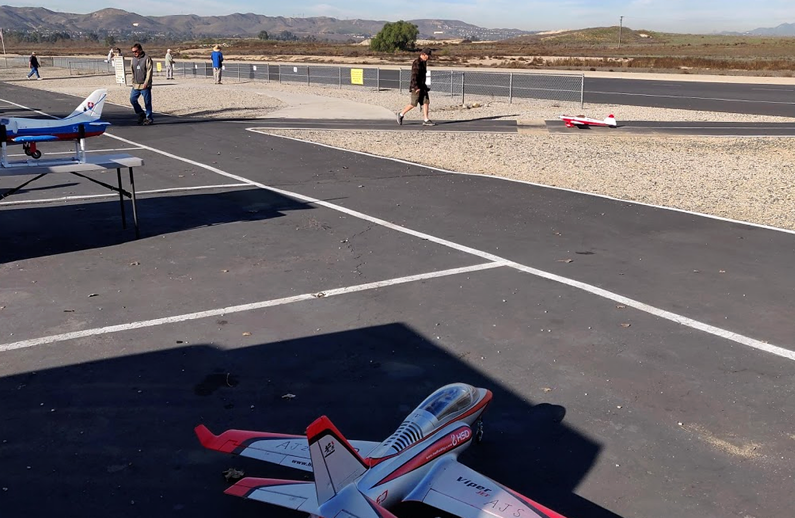 Model airplanes sit on the asphalt a Prado park airfield.