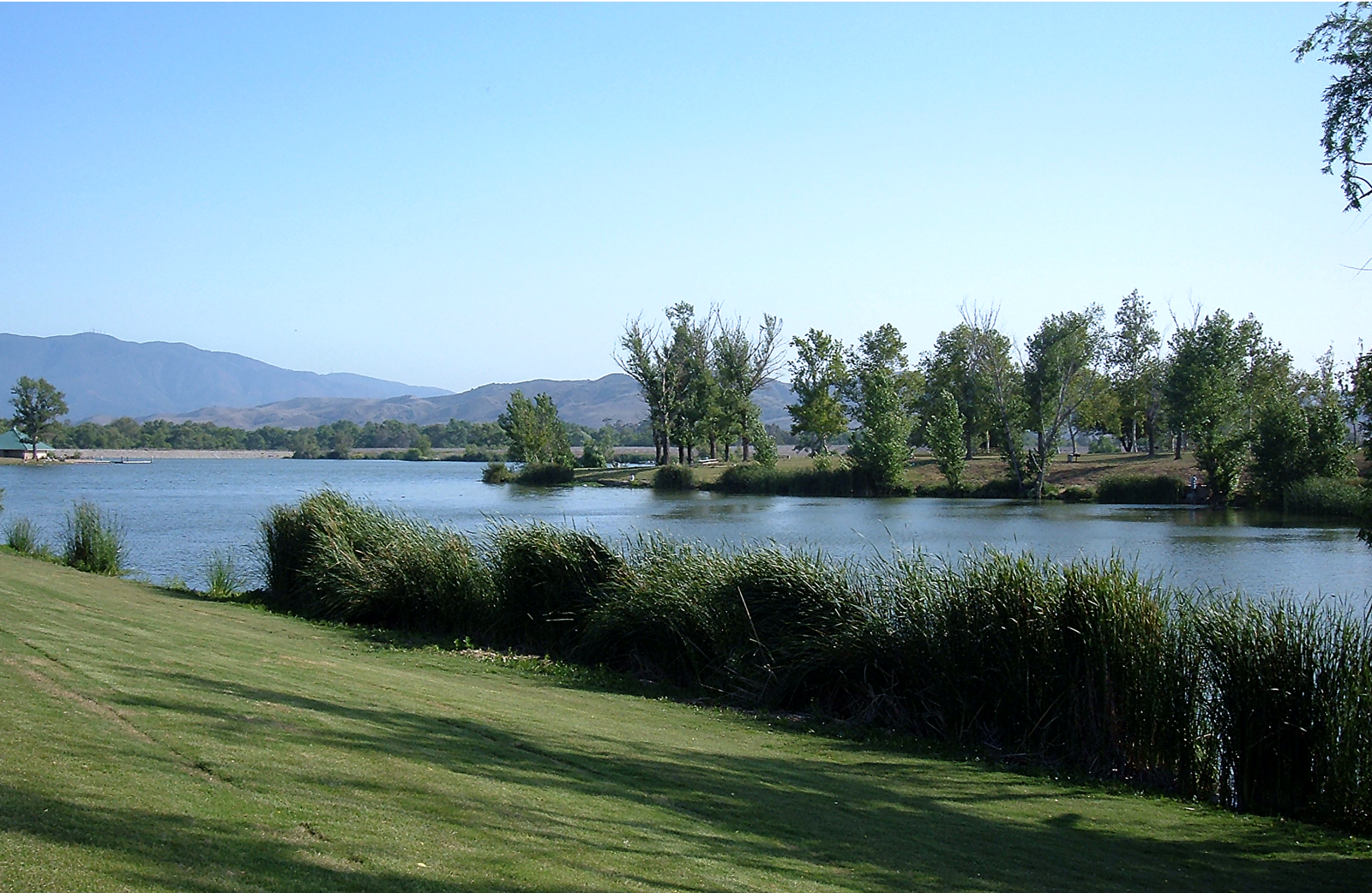 A side view of Prado lake with green grass.