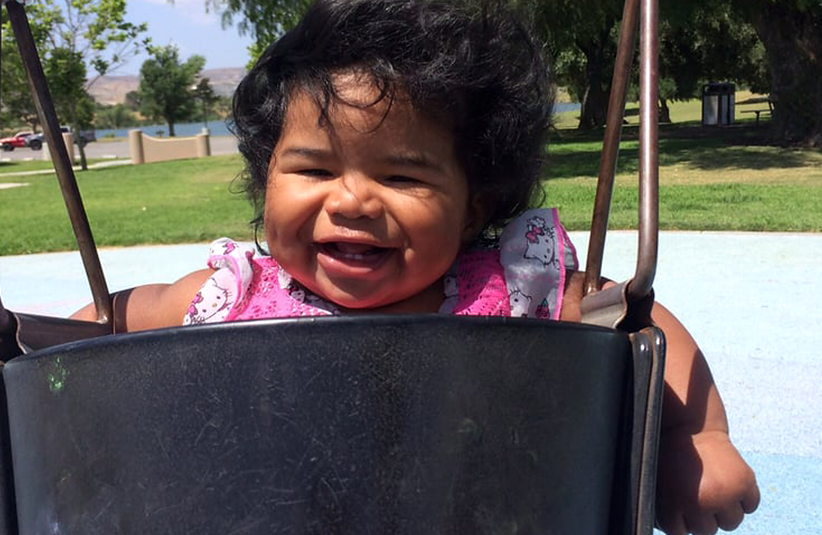 A smiling girl toddler swinging at Prado park.