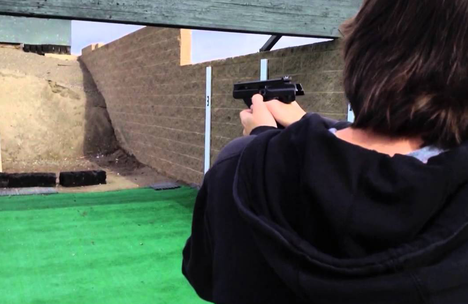 A woman shooting a gun at a target on a gun range..