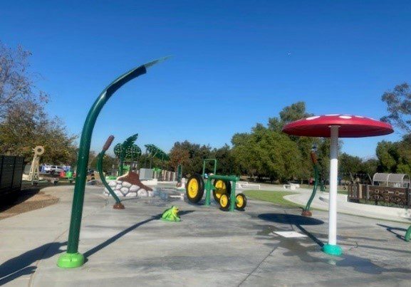 A large green tractor, mushroom and water apparatus represents the splash pad at Prado Regional Park.