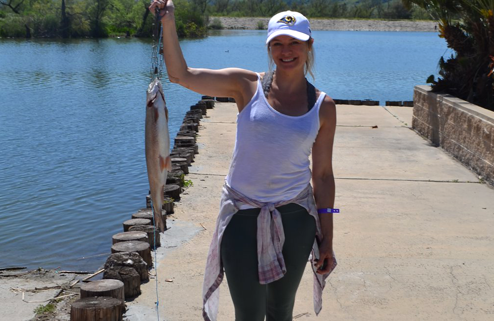 A woman holds up a bass fish she caught at Prado park.
