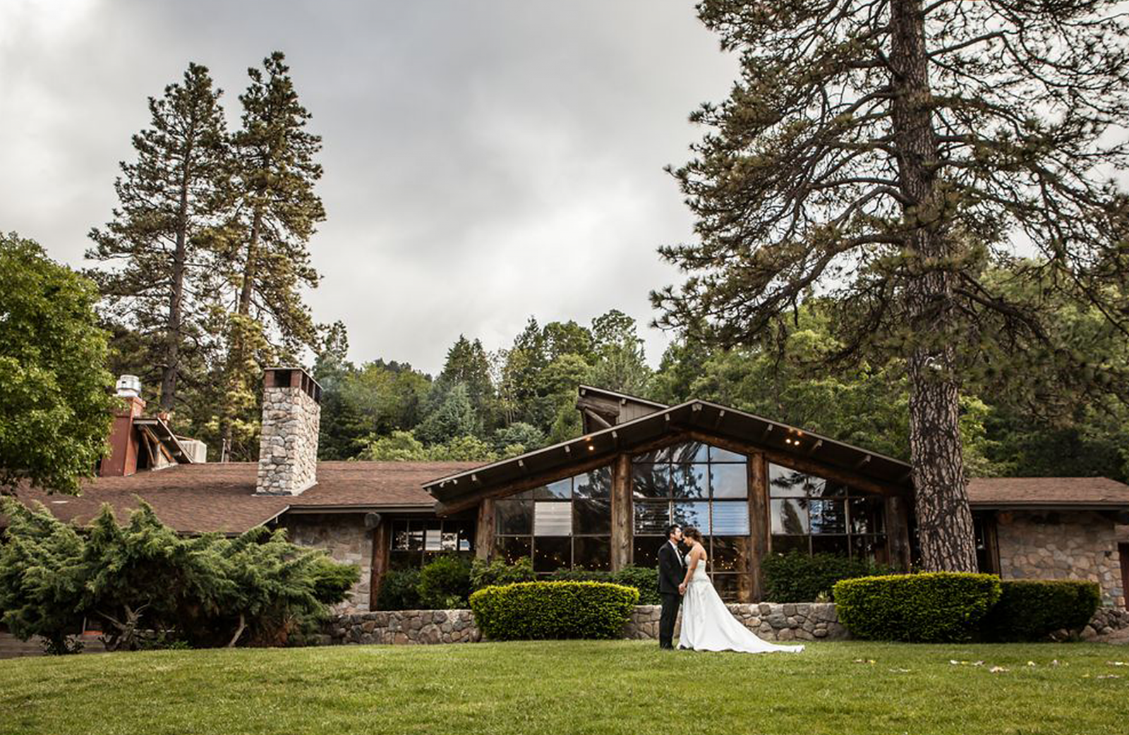 A man and woman on their wedding day as groom and bride kissing in front of the San Moritz lodge.