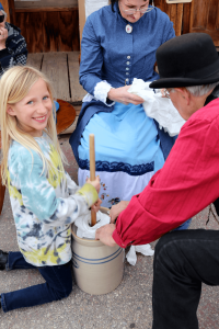A little girl learns how to churn butter at Calico California Days event in 2023.