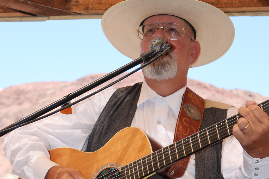 A male country performer holds a guitar at sings at Calico Bluegrass Festival in 2022.