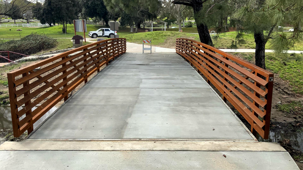A photo of a new bridge with concrete walkway and pre-fab wood railing at Glen Helen Regional Park.