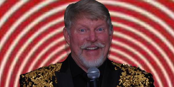 A man smiling holding a microphone in front of red and white spiral zanry background.