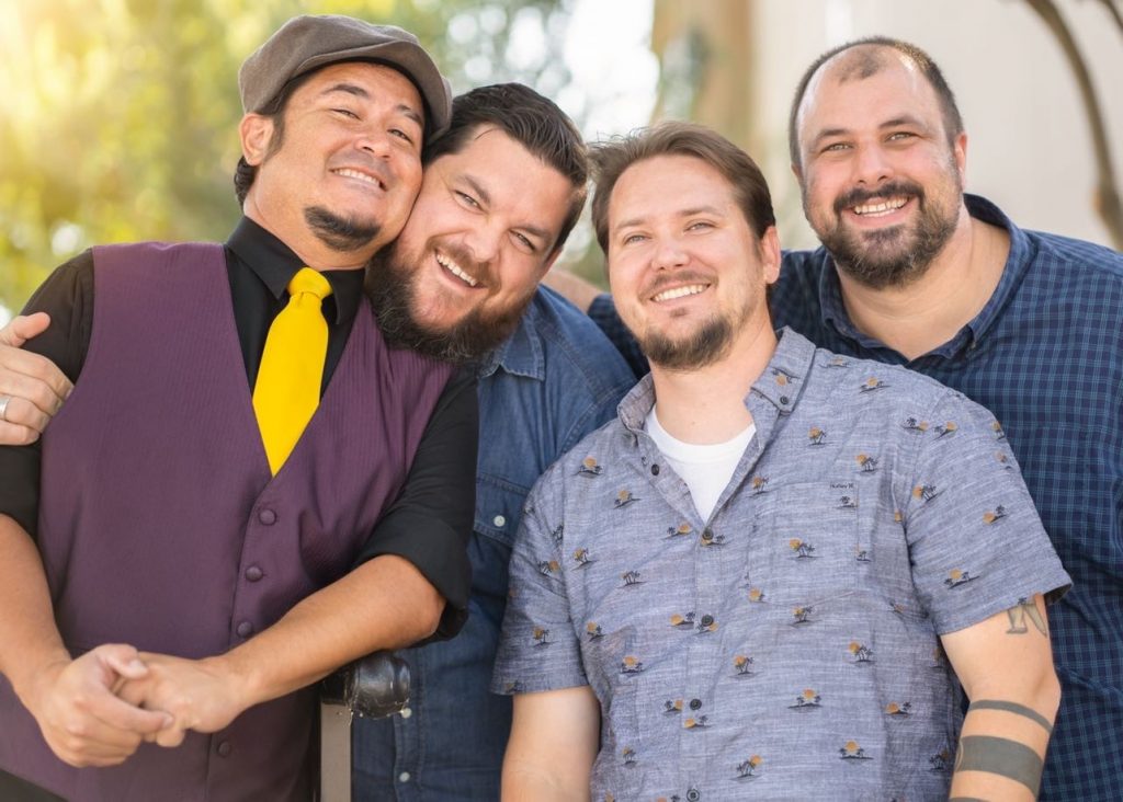 A group of four male musicians smiling.