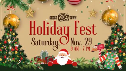 Large Christmas ornaments with garland and Christmas trees on the right and left with Santa Claus in the middle. An ugly sweater and Santa's mailbox with poinsettias and wrapped Christmas gifts near the left tree.