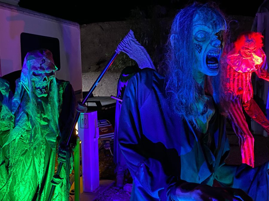 A campsite is decorated at night with large creepy monsters with lit with blue, red and green lights at Calico Ghost Haunt.