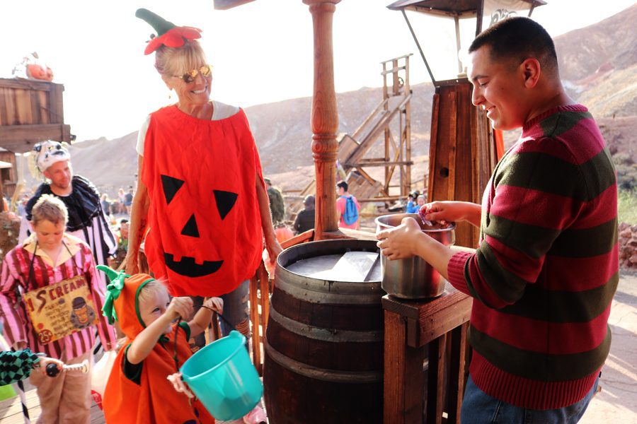A group of kids and a woman dressed in Halloween costumes get candy from a store at Calico Ghost Haunt.