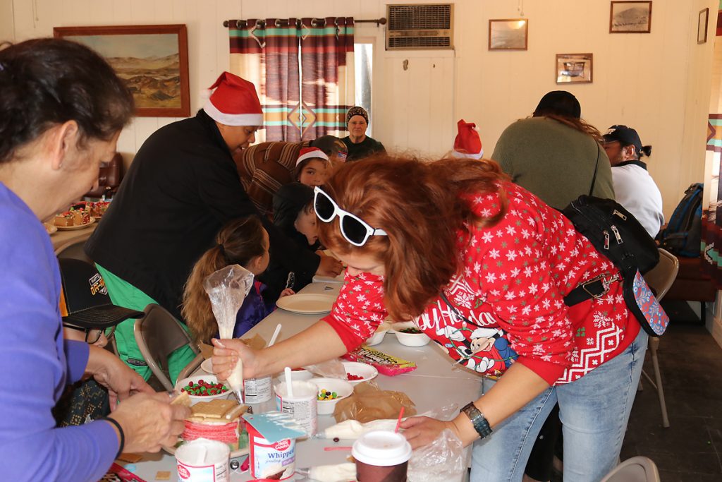 People build gingerbread houses on a table at Calico Holiday Fest.