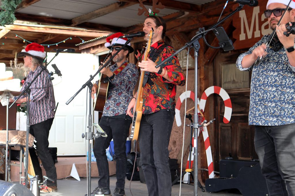 Four band member of the Storytellers Band play instruments on the Main Street Stage at Calico Holiday Fest.