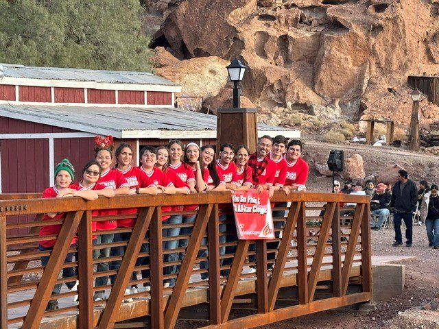 A group of young people stand alongside a rail on a bridge.