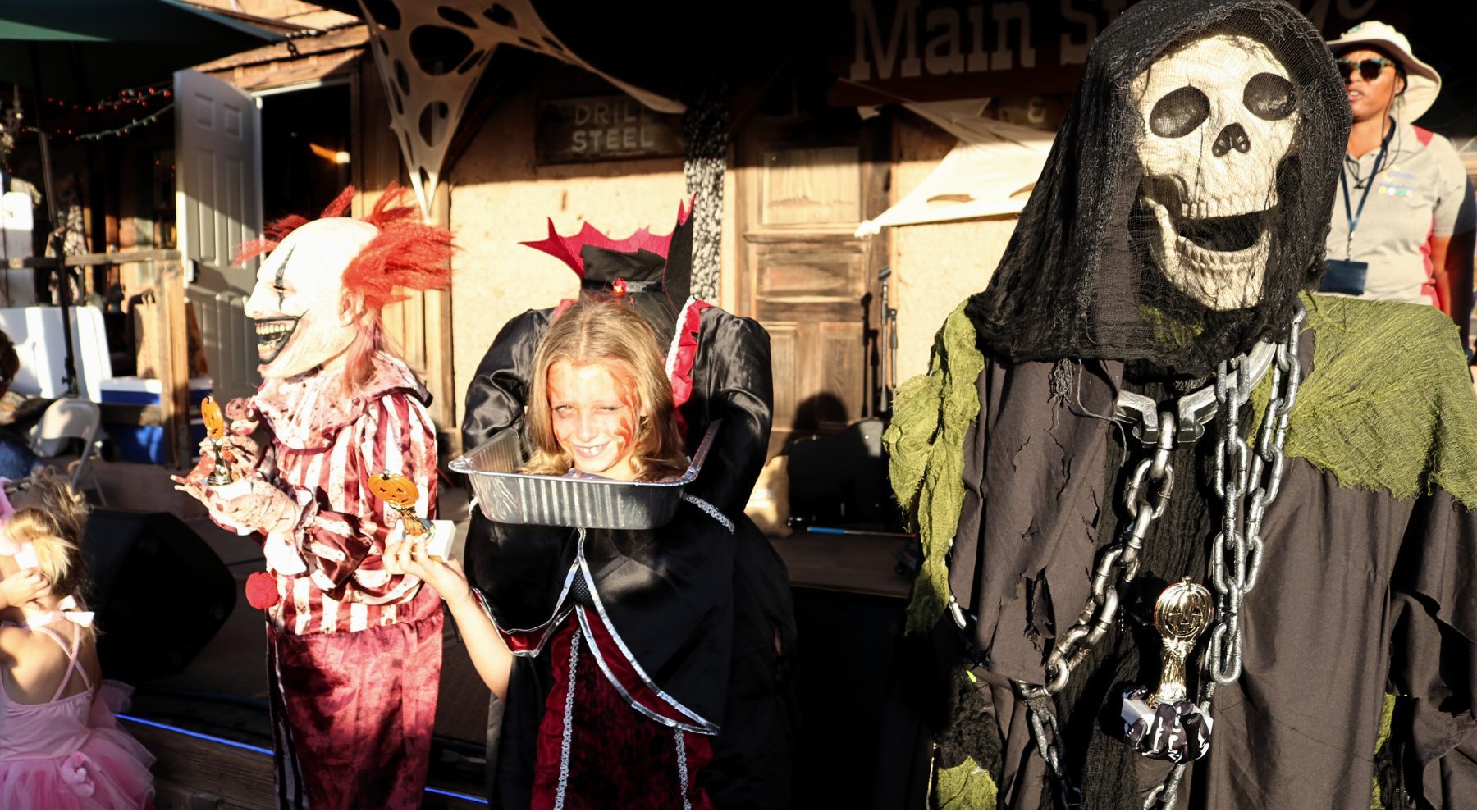 A group of three people dressed in Halloween costumes stand at Calico Ghost Town.