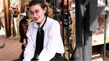 A young woman dressed in as Dracula sits and smiles at Calico Ghost Town.