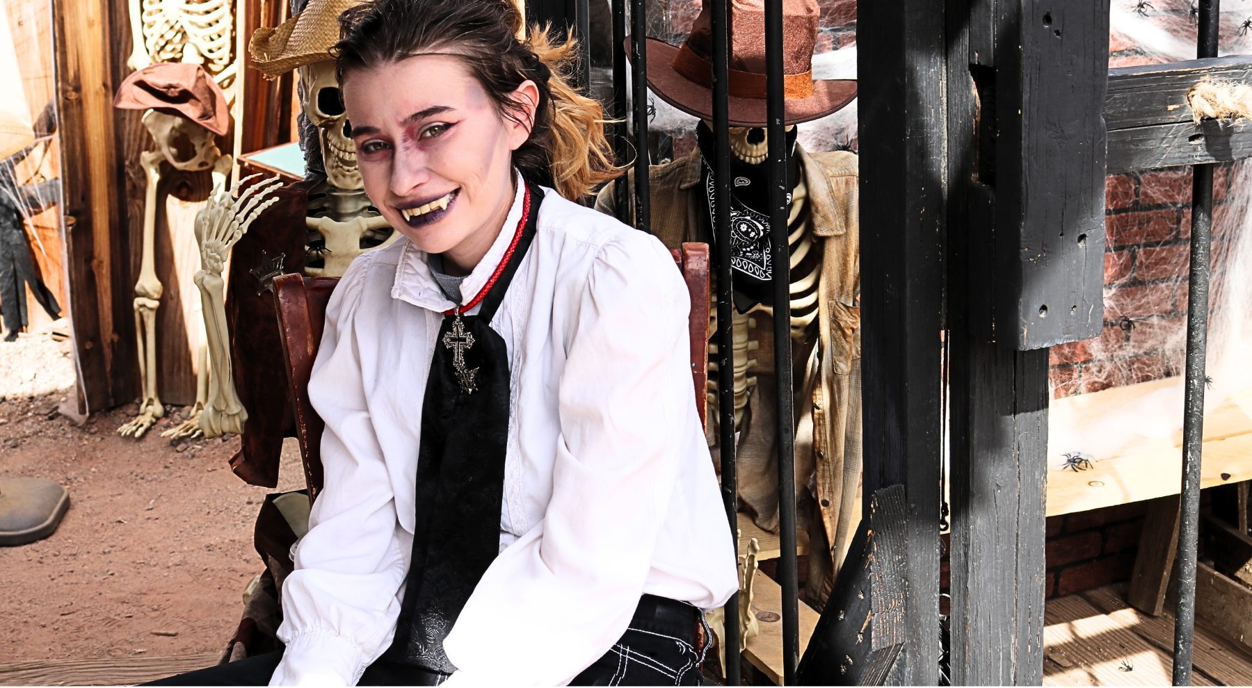 A young woman dressed in as Dracula sits and smiles at Calico Ghost Town.