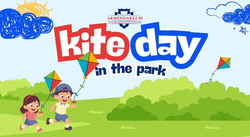 Colorful Kite Day in the Park graphic featuring two children running with kites across a grassy park. Additional colorful kites fly above green hills under a light blue sky with illustrated clouds and sun. Text reads “Kite Day in the Park” with San Bernardino County Supervisor Armendarez branding.